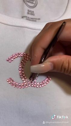 someone is doing something with pink beads on their t - shirt and holding a pen