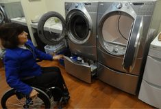 a woman in a wheel chair next to a washer and dryer