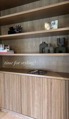 a wooden shelf with vases and books on it