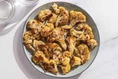 roasted cauliflower on a plate next to some water and a glass container with salt