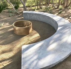 a concrete bench in the middle of a park with a bowl on it's side