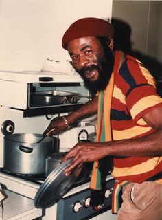 a man with a beard standing in front of an oven holding a frying pan