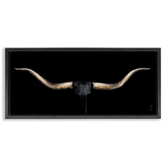 a bull's head with long horns is shown in black and gold framed art