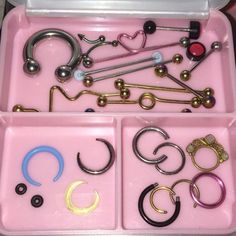 a pink box filled with lots of different types of rings and earring hooks on top of a table