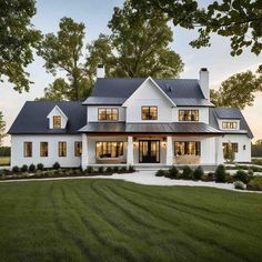 a large white house with lots of windows on the front and side of it, surrounded by grass