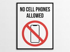 a sign that says no cell phones allowed in front of a white wall with a black frame