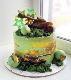 a cake with green frosting and decorations on the top is sitting in front of a window