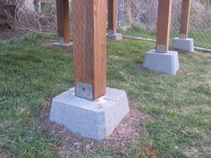 two cement pillars in the middle of a grassy area next to a chain link fence