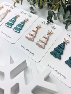 four christmas tree earrings on top of cards