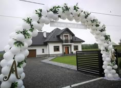 an arch made out of balloons and greenery is in front of a white house