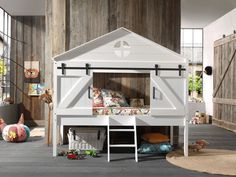 a white bunk bed with a wooden wall behind it and stuffed animals on the floor