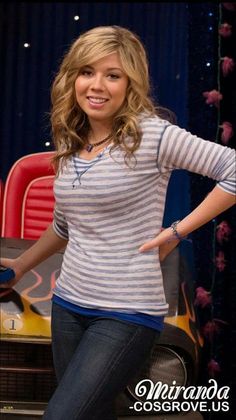 a woman standing in front of a red chair with her hands on her hips