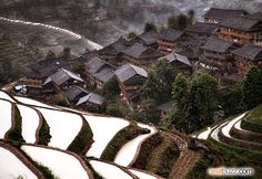 an aerial view of a village in china with rice terraces and houses on the hillside