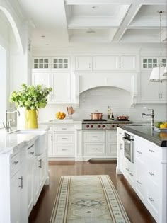 a large kitchen with white cabinets and wood flooring, along with an area rug