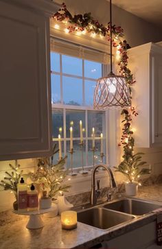 a kitchen sink under a window next to a christmas wreath with candles on the windowsill