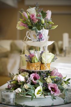 three tiered cake decorated with flowers and greenery on a table in a living room