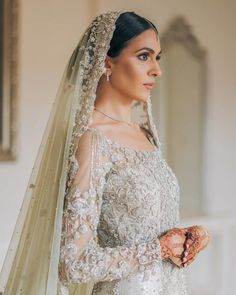 a woman wearing a wedding dress and veil with her hands on her hip, looking off to the side