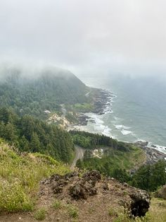 a scenic view of the ocean and mountains on a foggy, overcast day