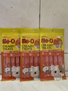 three bags of meo cat treats sitting on a counter