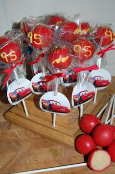 some lollipops with cars on them sitting on top of a wooden table