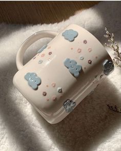 a white bag with blue bears on it sitting on top of a fluffy blanket next to a plant