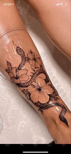 a woman's leg with flowers on it and a snake wrapped around the foot