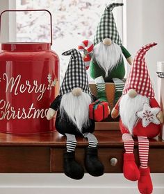 three christmas gnomes sitting on a table next to a canister and other holiday decorations