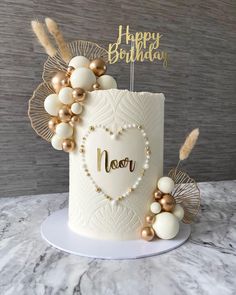 a white cake with gold decorations and a happy birthday sign on it's top