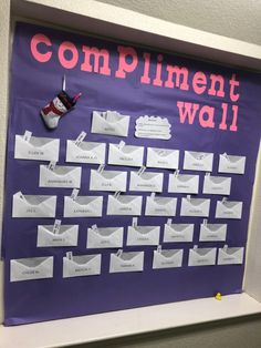 a purple bulletin board with white envelopes and pink writing on the bottom, which says compliment wall