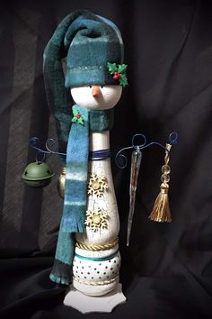 a snowman statue with scarf and hat on it's head, next to other ornaments