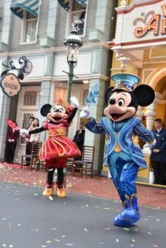 mickey and minnie dancing on the street in front of a building with confetti