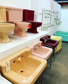 many different colored toilets and sinks on display in a room with white walls, flooring and concrete floors