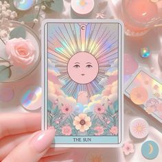 the sun tarot card surrounded by pink flowers and other items on a white surface