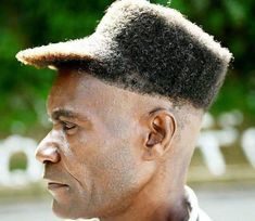 a close up of a person with a hat on his head and trees in the background