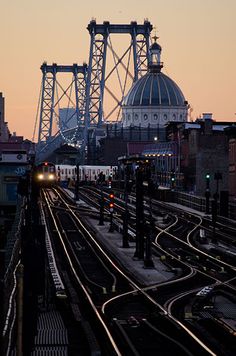 a train traveling down tracks next to a tall building with a dome in the background