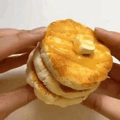 a person holding a stack of pancakes with butter on top