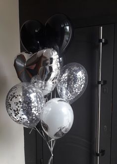 some balloons are hanging from the ceiling in front of a black door with white and silver confetti