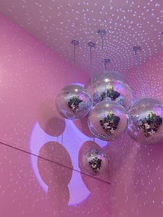 several disco balls hanging from the ceiling in a room with pink walls and white stars