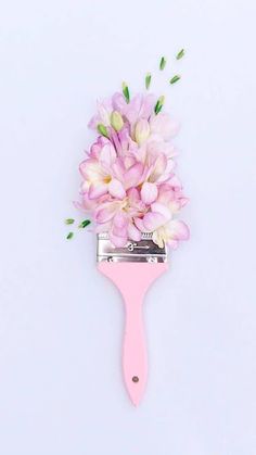 a pink hair comb with flowers on it sitting next to a white wall and blue background