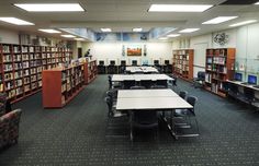 an empty library filled with lots of tables and chairs next to bookshelves full of books