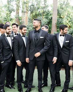 a group of men in tuxedos standing next to each other on the grass