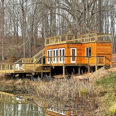 a small house sitting on top of a hill next to a body of water with trees in the background