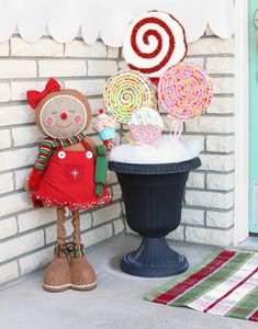 a gingerbread man standing next to a potted plant filled with lollipops