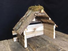 a birdhouse made out of wood with moss growing on the roof and side walls