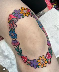 a woman's thigh with flowers and mushrooms on the lower part of her leg