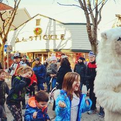 a large polar bear standing in front of a group of kids on a city street