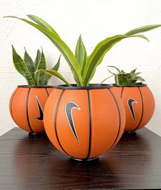 three orange basketball planters sitting on top of a wooden table