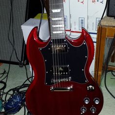 a red electric guitar sitting on top of a table