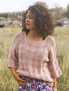 a woman standing in a field with her hands on her hips