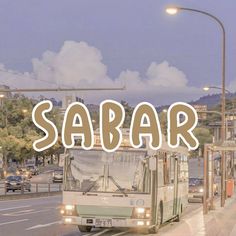 a bus driving down a street next to a tall building with the word sabar written on it